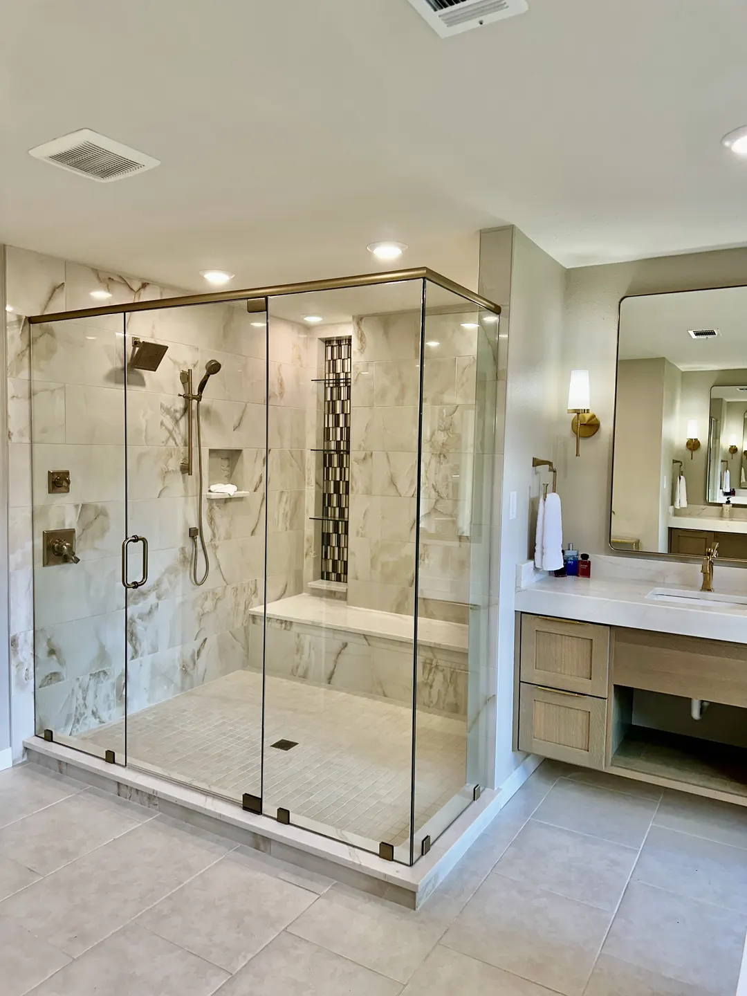 Glass enclosure in a tiled bathroom beside a double vanity